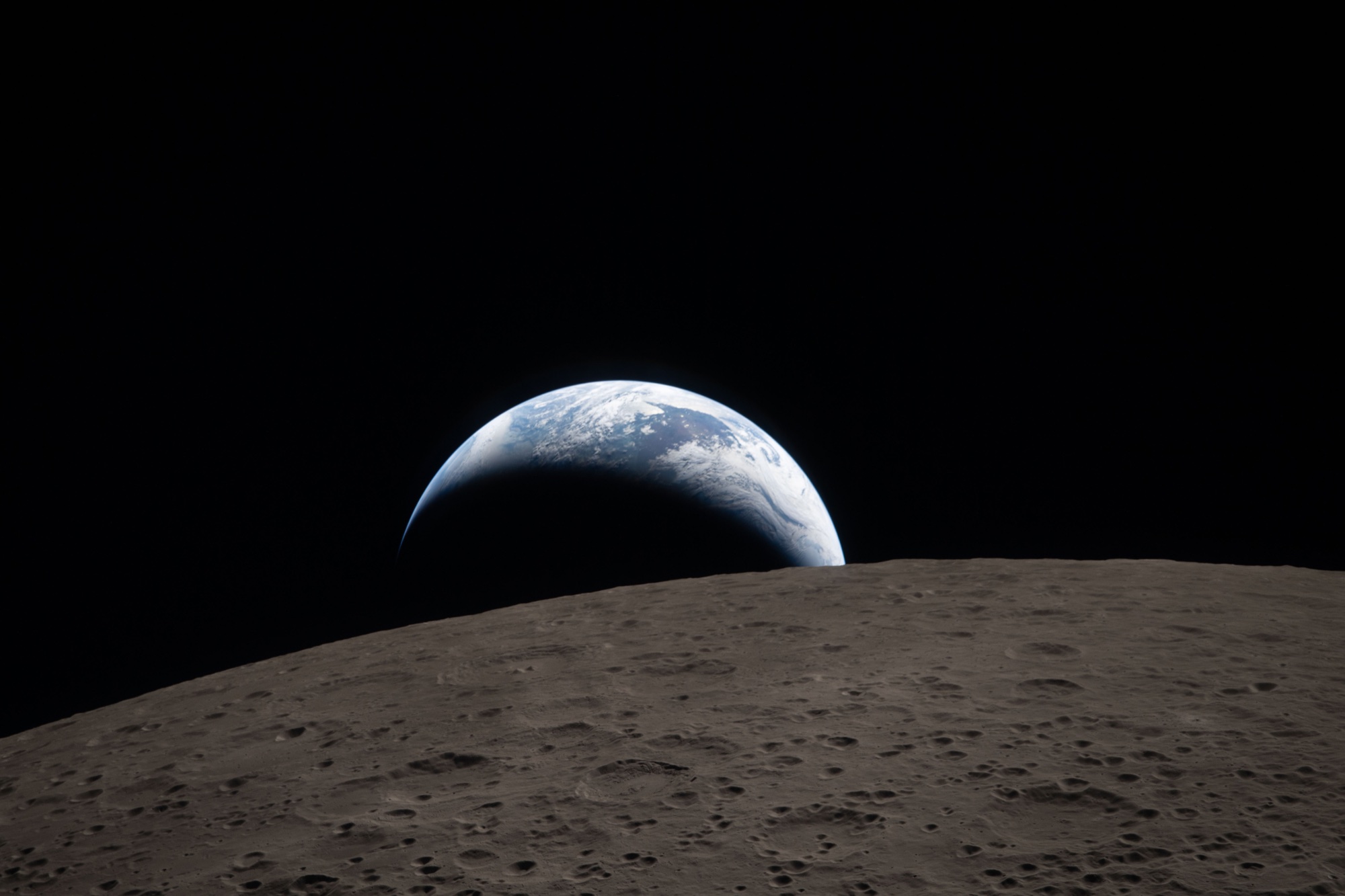 Earth beyond the cratered lunar horizon, photographed during Artemis II